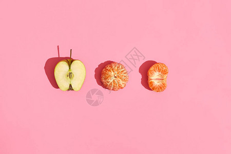 食品设计粉红色珊瑚背景上一半苹果去皮普通话和一半去皮普通话的组成模拟图片