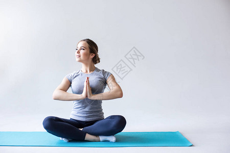 在蓝瑜伽垫子上的露珠位置的女运动员灰色背图片