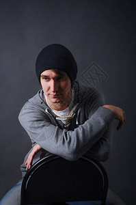 黑帽子牛仔裤和灰色运动衫工作室黑暗灰色背景的年轻图片