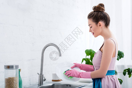 在厨房用粉红色橡胶手套洗碗机洗图片
