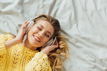 坐在床上的耳机里听着带复制空间的音乐美丽的笑着年图片