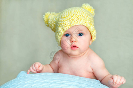 一个穿着黄色编织帽子的可爱新生女婴的肖像假扮在图片