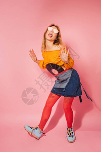拥有粉红背景的旧式黑乙烯球纪录的时尚装女郎背景图片