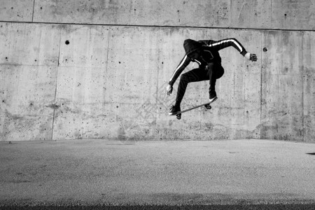 男滑板运动员在城市的滑板上跳背景图片