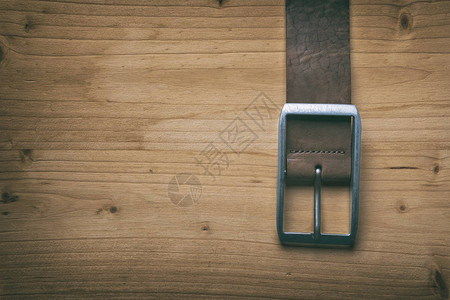 木板上带扣的棕色皮革腰带图片