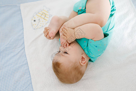 可爱的宝把脚放在嘴里可爱的小女婴吸吮自己的脚健康的孩子在更衣桌上图片