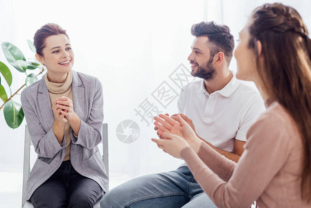 在集体治疗期间男女坐在一起欢呼着微笑背景图片