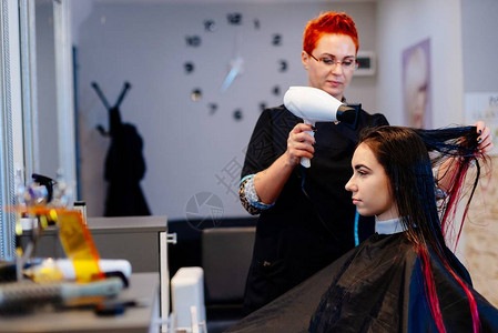 妇女理发师用烘发机干客户毛发图片