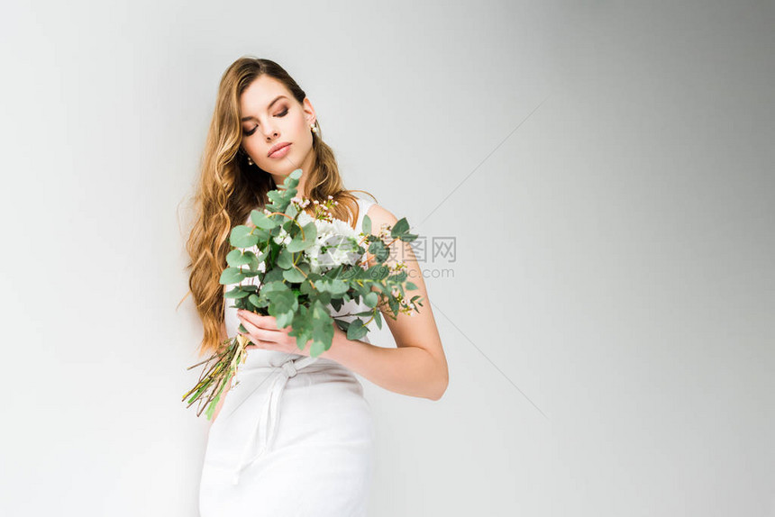 穿着优雅服装的女孩拿着和菊花的束白色的叶子图片