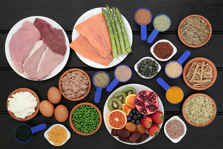 健身保健食品含有高蛋白肉类鱼类乳制品补充粉鱼油和小球藻片草药绿茶蔬菜和水果深色木背景图片