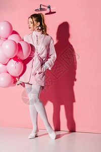 美丽的年轻美女拿着气球手站在粉红色背景图片