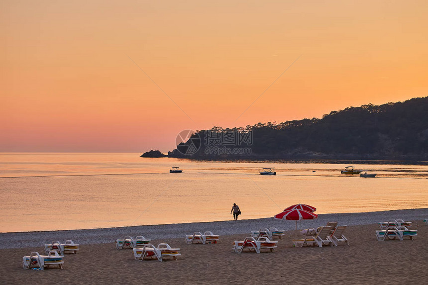 海景与日落时的山脉和海岸的轮廓滑翔伞在金色的阳光下飞过厄吕代尼兹海滩暑假休闲和滑翔伞的土图片