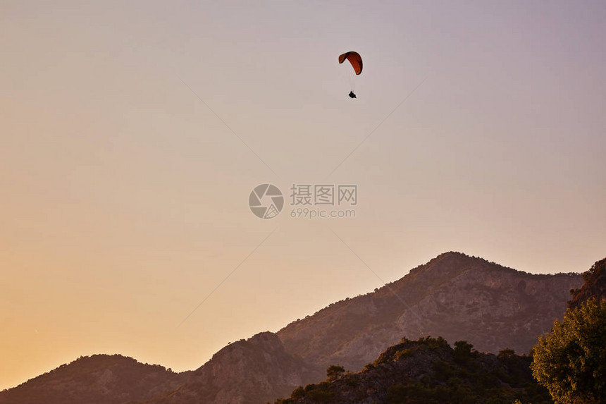 滑翔伞剪影以美丽温暖的日落色彩飞过迷雾笼罩的山谷充满自由的运动活跃壁纸背景与空间图片