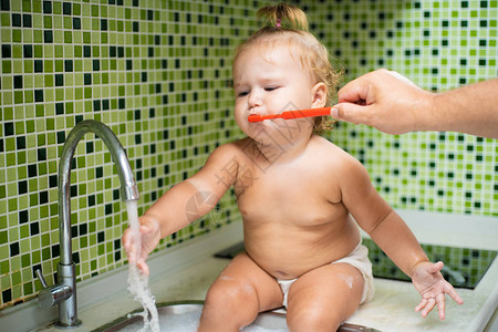 可爱的蹒跚学步的女孩在浴室里刷牙可爱的宝坐在水槽里爸图片