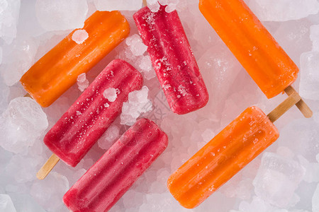冰块上的橙子和草莓冰棒顶视图图片