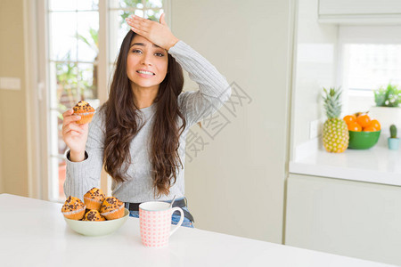 吃巧克力松饼和喝咖啡的年轻女人用手捂着头图片