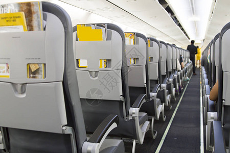 机上坐着乘客和穿制服空姐的飞机的内部航班高清图片素材
