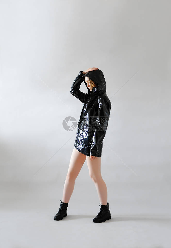 穿着黑色防雨衣带兜帽和低鞋的穿黑衣服雨衣的时髦瘦小女孩图片