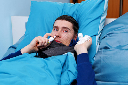 病人用鼻喷雾躺在床上时带着蓝枕头图片