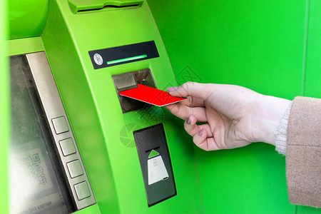 女人在自动取款机中插入信用卡收回钱图片