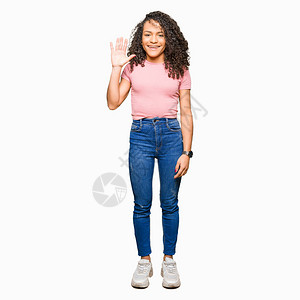 穿着粉红色T恤的卷发年轻美女拿着五指向上满脸自信和快乐地微笑着图片