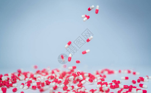 对粉红色白胶囊丸的选择关注落到白色桌子上合理使用抗生素药物抗生素耐药医药行业背景图片