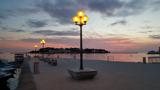 日落时当地海边石码头的三座高街灯连续三图片