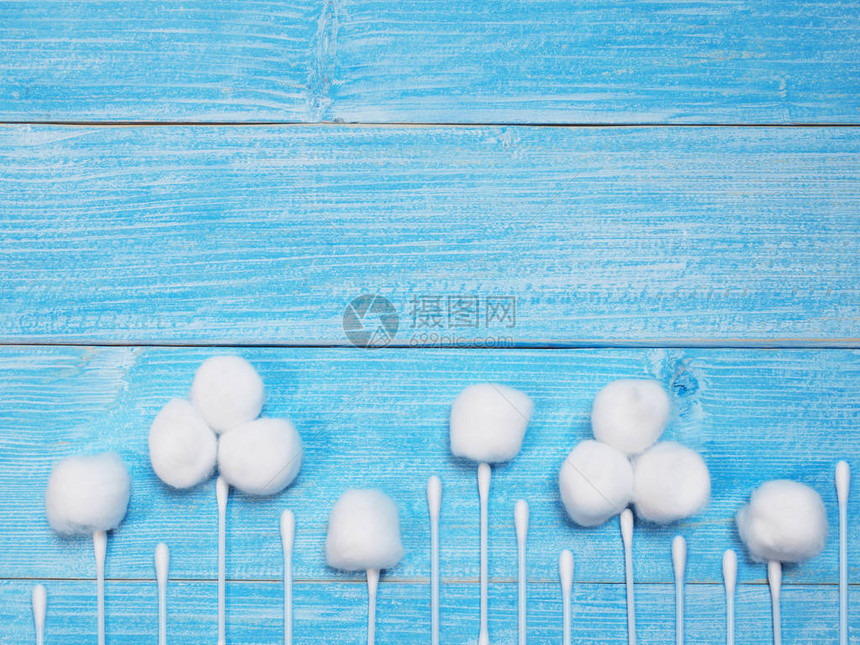 白色吸收棉花球和木制蓝底的棉花芽作为图片