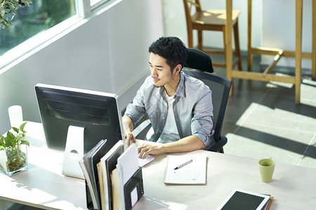 使用台式计算机在办公室工作的年轻亚洲商务人员高角度视角图以台式计图片