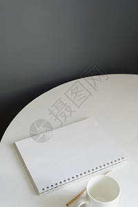 阁楼厨房内部的白色木桌上放着陶瓷咖啡杯和铅笔的空白笔记本图片