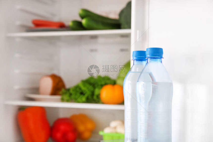 打开冰箱里的瓶装水图片