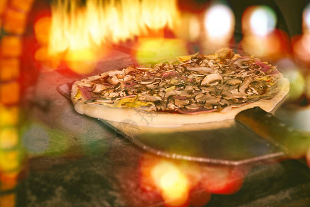 一把铲子上的意大利新披萨正放进一个传统的烧图片