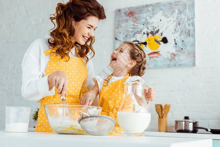 快乐的母亲和兴奋的女儿在厨房一起做饭图片