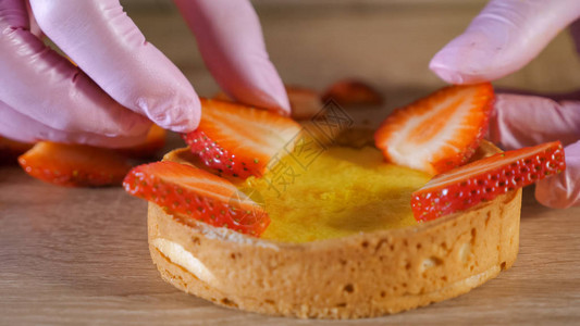 糕点厨师把草莓切片加奶油放在饼干上做一个小蛋糕图片