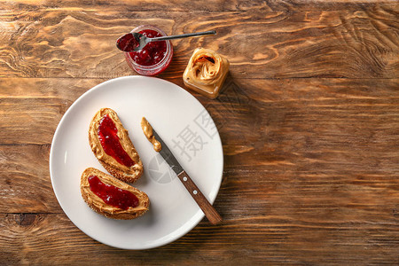 木桌上有美味花生酱和果酱的面包图片