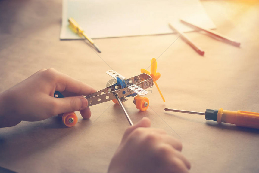 孩子们手里拿着玩具铁飞机桌上有螺丝刀的飞机金属构造器图片