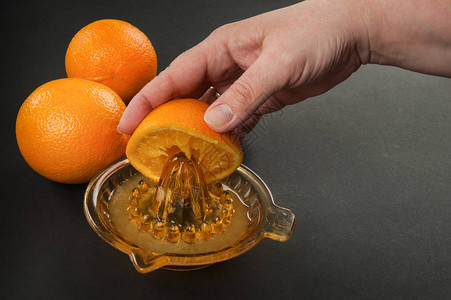 深色背景中带橙子的手持式手动榨汁机图片