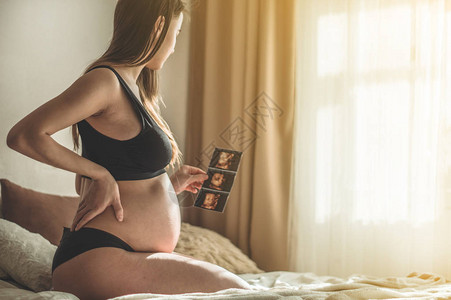 孕妇手持超声图像怀孕保健妇科医学的概念等待婴儿的年轻母亲文本图片