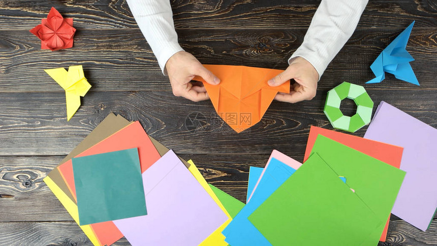 手折叠纸做图男人弯曲橙色纸做折纸木桌上的一组折纸人物图片