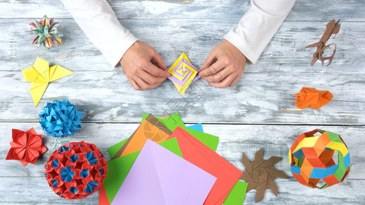 男人的手创造美丽的折纸玩具木桌上的纸折模型的集合工作才能和技能日图片