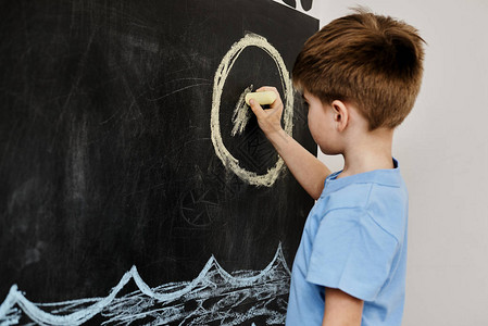 黑板上用粉笔作画的小男孩图片