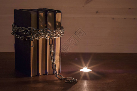 以燃烧的蜡烛用链条包着的书和蜡烛为灯光图片