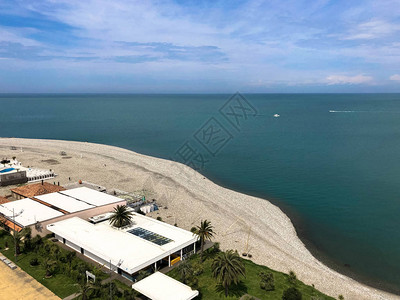 沙滩的顶端是沙海绿棕榈树和建筑热带温暖的夏日度假胜地上图片