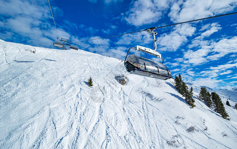 在白雪皑的山区滑雪缆车在明亮的阳光下图片
