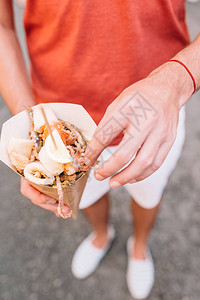 意大利街头食品在男手中烤海鲜鱼虾图片
