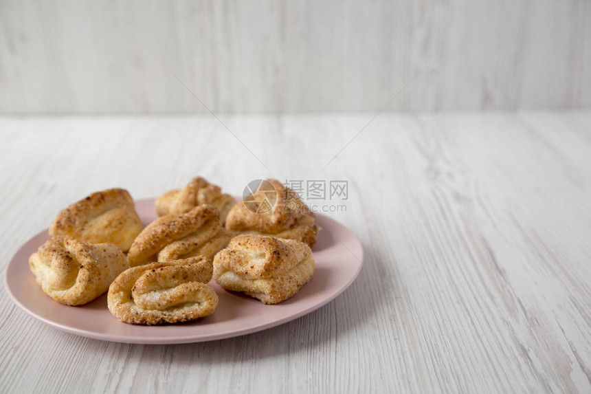 白木板表面的粉红色盘子上有家庭烤鸡肉干酪饼干侧面视图片