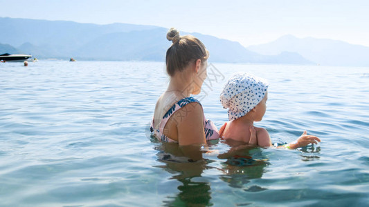 年幼母亲与幼儿孙一起在炎热的夏日在海中游泳人们图片素材