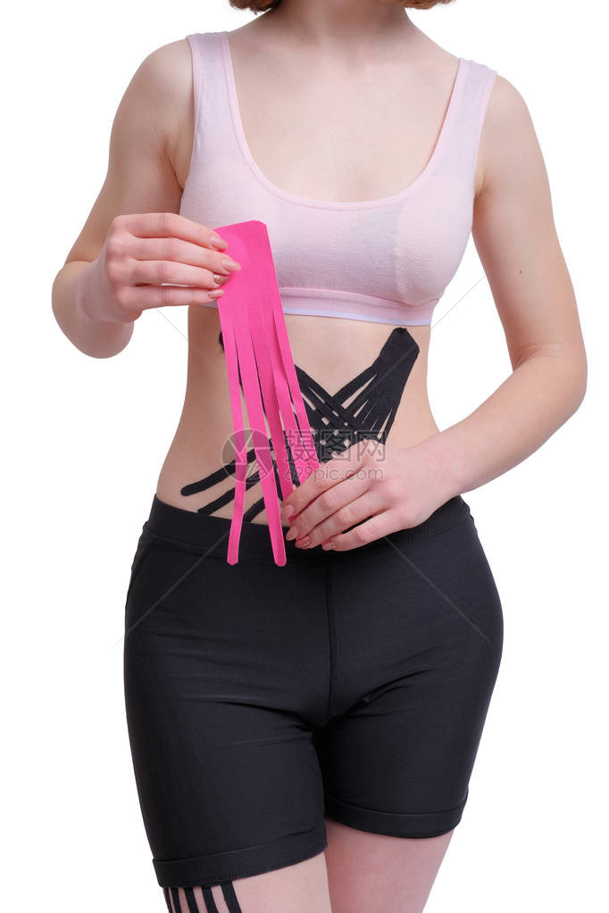 年轻女孩的手在腹部上用粉红色运动生理胶带在风学背景垂直图片
