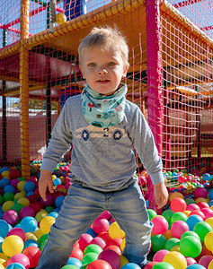 快乐的小男孩在彩色儿童游戏球场玩耍幸福的杂技游戏概念高图片