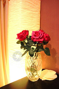 一束五朵红玫瑰花晚上在桌边水晶花瓶里用图片